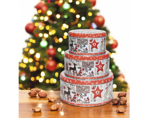 Ein Set aus drei runden, weihnachtlich dekorierten Blechdosen, gestapelt vor einem Weihnachtsbaum.
