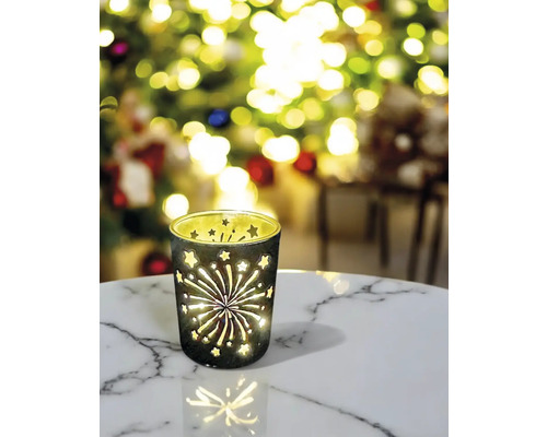 Windlicht aus Glas mit Sternen und Feuerwerksmuster auf einem Tisch