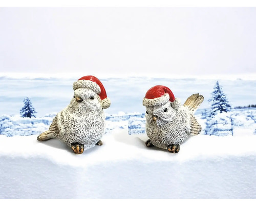 Zwei dekorative Vögel mit Weihnachtsmützen auf einer Schneefläche