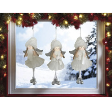 Trois décorations d''anges de Noël blanches suspendues devant une fenêtre.