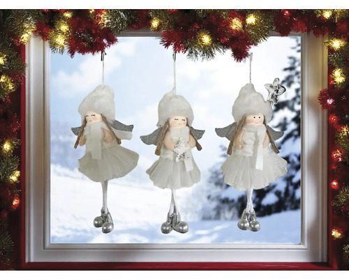 Drei weisse Weihnachtsengel-Anhänger hängen vor einem Fenster.