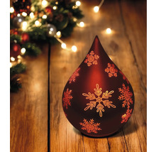 Lampe de Noël décorative en forme de goutte avec motif de flocon de neige sur une table en bois, éclairage festif en arrière-plan.