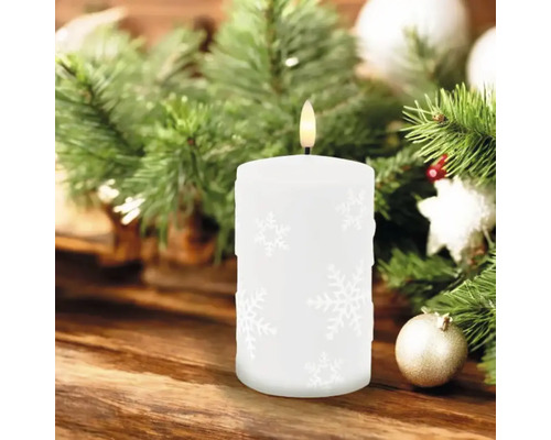 Bougie LED décorative avec motif de flocons de neige sur une table en bois avec des branches de sapin et des boules