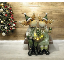 Figurines décoratives d''élans avec sapin de Noël et éclairage sur un banc devant un sapin de Noël