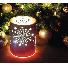 Dekoratives Windlicht mit Sternen und Feuerwerk-Motiv vor einem Weihnachtsbaum