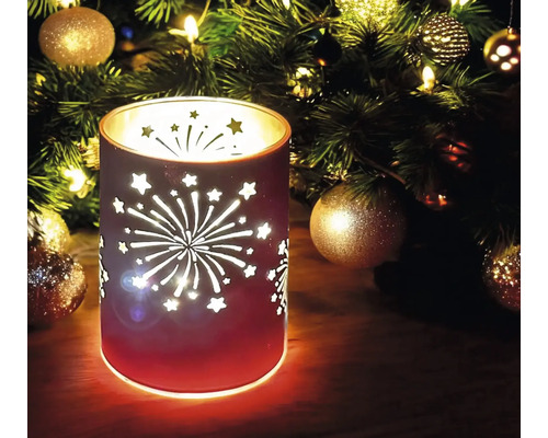 Dekoratives Windlicht mit Sternen und Feuerwerk-Motiv vor einem Weihnachtsbaum