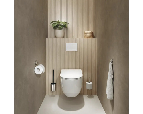 Salle de bains avec WC suspendu, brosse de toilette, support de papier toilette et serviette