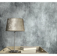 Nahaufnahme einer Wandtapete mit abstraktem Muster neben einer Lampe und Büchern.