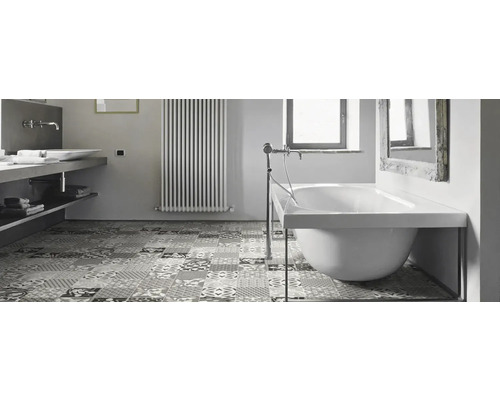 Salle de bains avec baignoire, lavabo, radiateur et carrelage à motifs