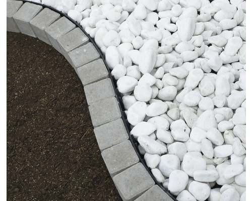 Gros plan sur des bordures de gazon grises, du paillis et du gravier décoratif dans le jardin.