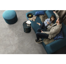 Wohnzimmer mit grauen Bodenfliesen in Steinoptik, Sofa, Hocker und Couchtisch