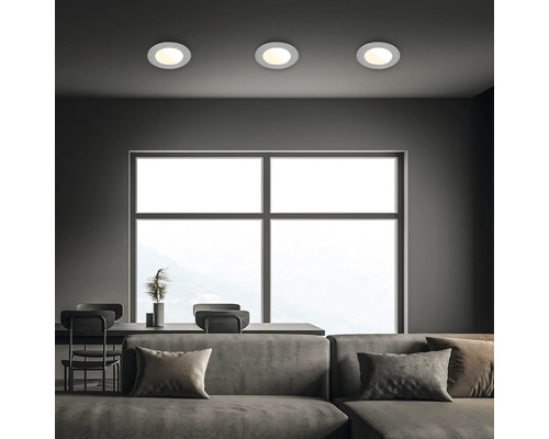 Innenraum mit Sofa, Tisch und drei runden Deckenleuchten