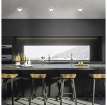 Cuisine moderne avec table de bar, tabourets de bar et spots encastrés pour une ambiance lumineuse.