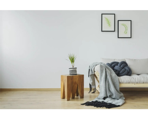 Helles Zimmer mit Holzbeistelltisch, Pflanze, Sofa, Decke und Kissen
