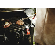 Barbecue avec des aliments et une personne tenant une pince à barbecue