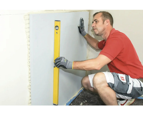 Un homme aligne une plaque de construction avec un niveau à bulle