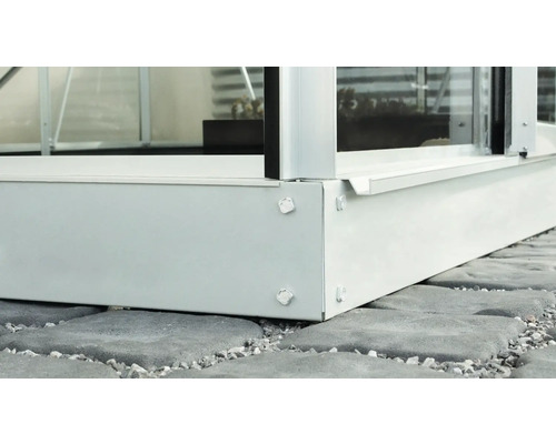 Vue détaillée des fondations métalliques d''une serre sur des pavés.