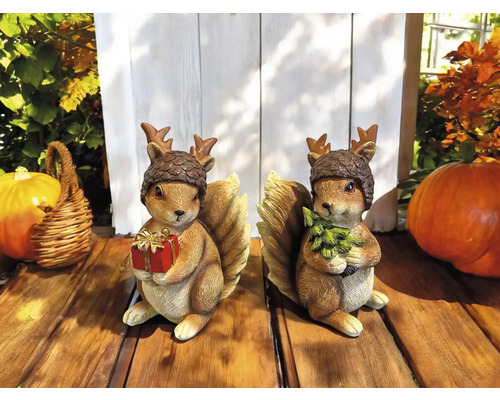 Zwei Eichhörnchenfiguren mit Nuss-Mützen, die Geschenk und Tannenbaum halten