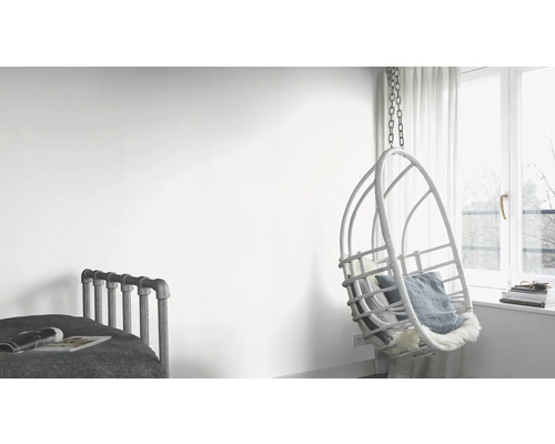 Pièce lumineuse avec lit et fauteuil suspendu en rotin près de la fenêtre