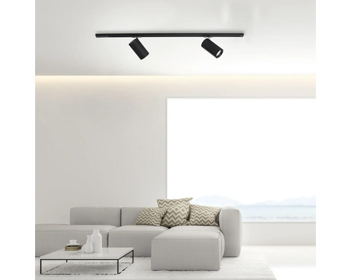 Zwei schwarze Deckenstrahler an einer Schiene in einem hellen Wohnzimmer.
