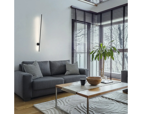 Wohnzimmer mit grauem Sofa, Holztisch und moderner Wandleuchte