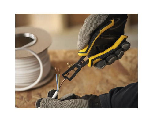 Une personne utilise une pince à dénuder sur un câble. Un rouleau de câble se trouve à l''arrière-plan.