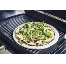 Pizza sur une pierre à pizza sur un barbecue