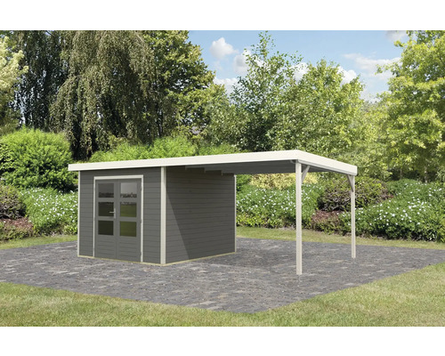 Abri de jardin avec annexe sur pavés devant des arbres