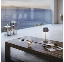 Stimmungsvolles Ambiente mit Tischlampe, Kerzenlaternen und einer Tasse Kaffee auf einem Holztisch