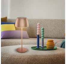 Szene mit Lampe, Kerzen und Dekorationsartikeln auf einem Tisch vor einem Sofa.