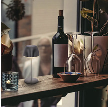 Dekorative Tischleuchte neben Weinflasche und Gläsern auf einem Regal