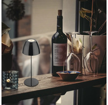 Dekorative Szene mit einer Tischleuchte, einer Flasche Wein und zwei Weingläsern auf einem Regal