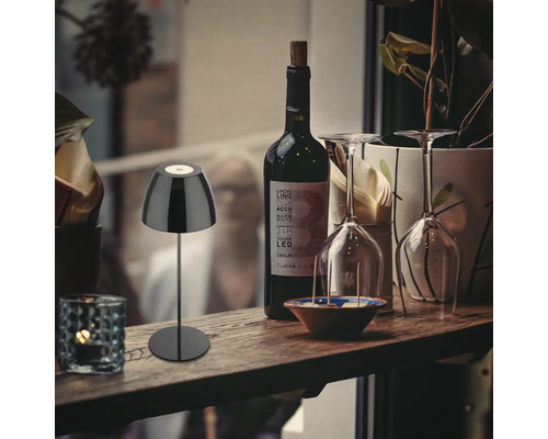 Dekorative Szene mit einer Tischleuchte, einer Flasche Wein und zwei Weingläsern auf einem Regal