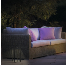 Gartenszene mit Rattan-Lounge-Sofa, Kissen und dekorativer Laterne für den Aussenbereich