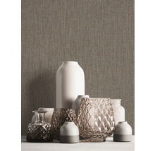 Divers vases décoratifs sur une table devant un mur texturé.