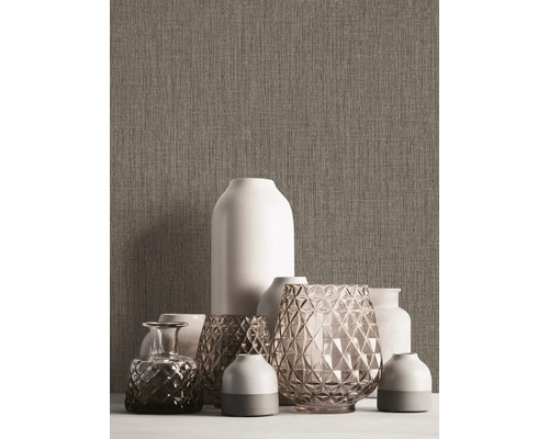 Divers vases décoratifs sur une table devant un mur texturé.