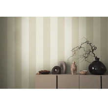 Dekoratives Arrangement auf einem Schrank vor einer gestreiften Tapete.