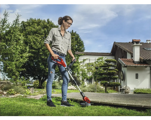 Femme utilisant un coupe-bordure sans fil dans le jardin.