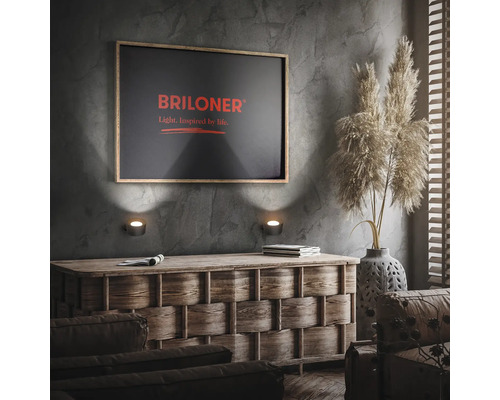 Wohnzimmer mit Kommode, Wandleuchten und Briloner Logo