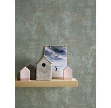 Dekorative Häuser und eine Fotografie auf einem Regal vor einer Wand mit Muster