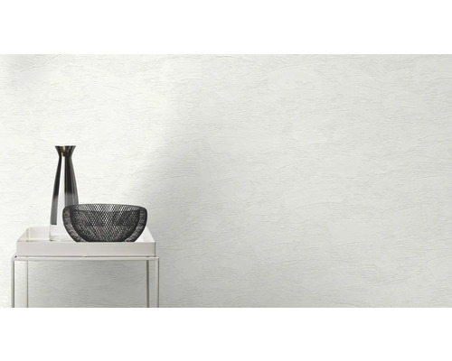 Vase décorative et bol sur une petite table devant un mur avec une texture de plâtre.