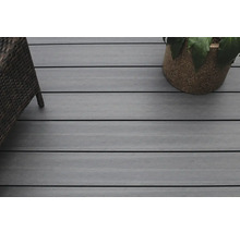 Gros plan d''une terrasse avec des planches en bois, un fauteuil en rotin et un pot de fleurs.