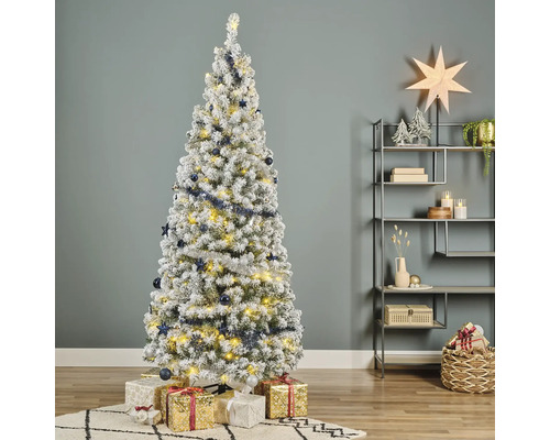 Sapin de Noël décoré et enneigé avec des cadeaux dans le salon