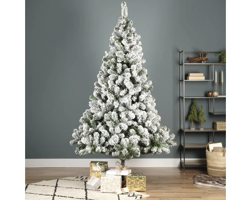 Sapin de Noël décoré et enneigé avec des cadeaux dans le salon.