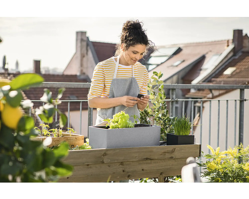 Femme sur un balcon avec un potager surélevé et des plantes