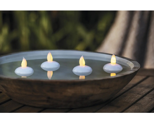 Dekorative Schale mit vier schwimmenden LED-Kerzen auf einem Holztisch