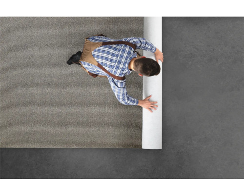 Ein Handwerker rollt einen Teppich aus.