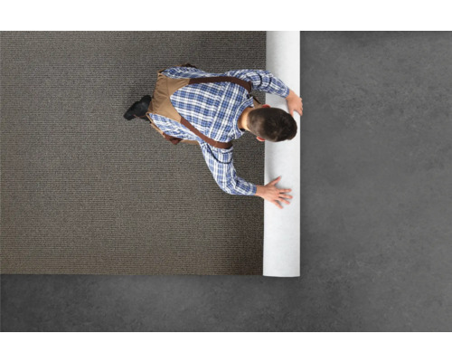 Un homme déroule un tapis sur le sol