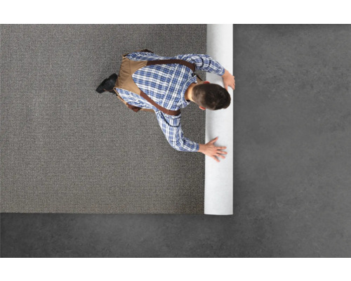 Mann verlegt Teppichboden in einem Raum