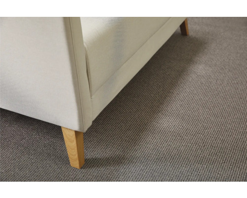 Detailansicht eines weißen Sofas mit Holzfüßen auf einem grauen Teppich